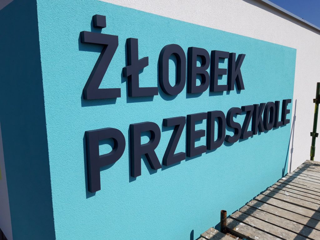 Napisy przestrzenne 3D wycięte ze styroduru i pomalowane farbą fasadową na budynku przedszkola i żłobka w Swrzędzu.